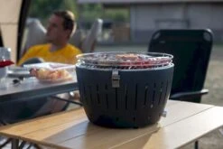 LotusGrill XL Hybrid Houtskoolbarbecue - Rood 22 LotusGrill XL Hybrid Houtskoolbarbecue - Rood -Buitenuitrusting lotusgrill in gebruik met toppy shirtje 2